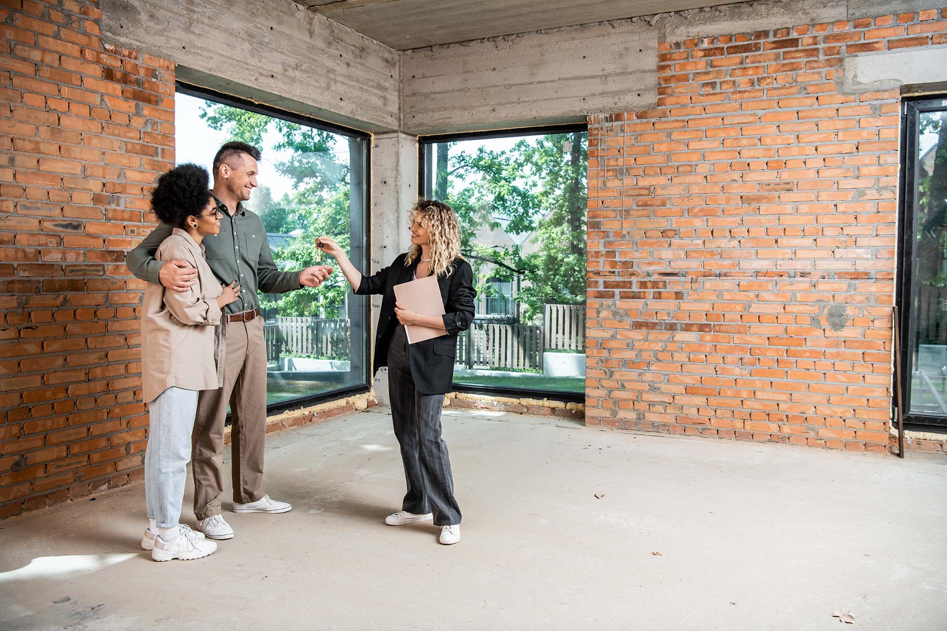 real estate agent giving keys to interracial couple in new cotta